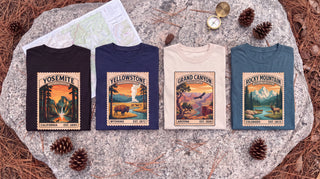 Four vintage stamp national park long sleeve shirts laid flat on a granite trail