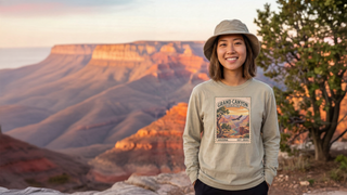 Woman in a bucket hat wearing a Grand Canyon National Park vintage stamp shirt at the canyon rim at sunset