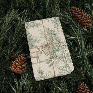 Present wrapped in rustic deer and pine tree gift wrap tied with twine on evergreen boughs