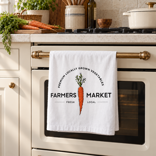 Artisan Grove Farmers Market carrot tea towel hanging on a cream kitchen oven