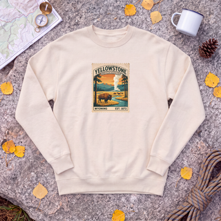 Natural cream Yellowstone National Park sweatshirt with vintage bison and Old Faithful stamp, flat-lay on granite with trail map