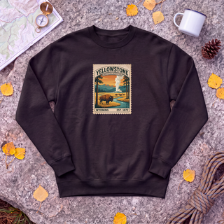 Black Yellowstone National Park sweatshirt with vintage bison and Old Faithful stamp, flat-lay on granite with trail map
