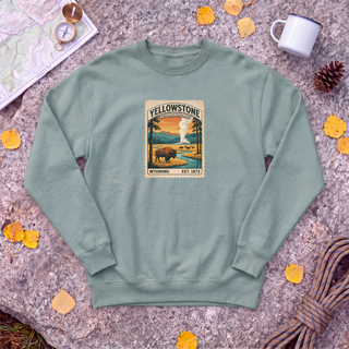 Cactus sage green Yellowstone National Park sweatshirt with vintage bison and Old Faithful stamp, flat-lay on granite with trail map