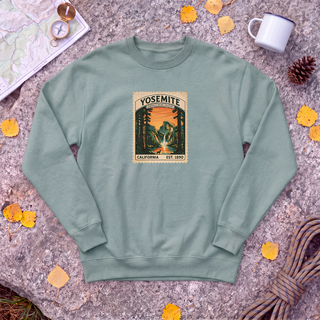 Cactus sage green Yosemite National Park sweatshirt with vintage Half Dome stamp, flat-lay on granite with trail map and compass