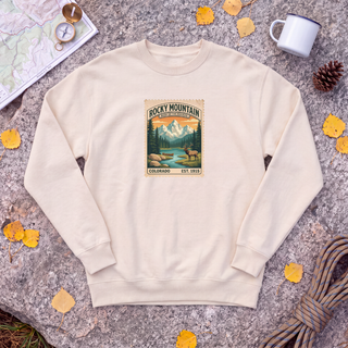 Natural cream Rocky Mountain National Park sweatshirt with vintage elk and mountain stamp, flat-lay on granite with trail map