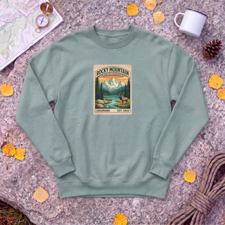 Cactus sage green Rocky Mountain National Park sweatshirt with vintage elk and mountain stamp, flat-lay on granite with trail map