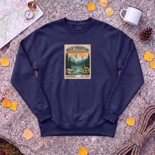 Navy Rocky Mountain National Park sweatshirt with vintage elk and mountain stamp, flat-lay on granite with trail map