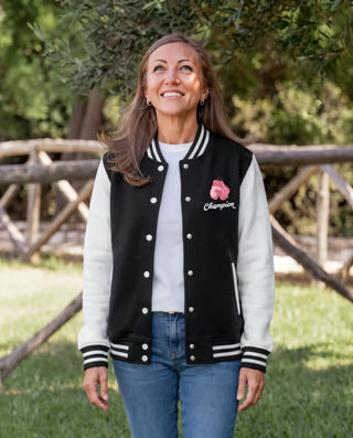 Woman wearing the black and white Breast Cancer Champion varsity jacket with pink boxing gloves and Champion script on the chest