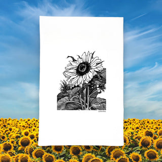 Sunflower cotton tea towel displayed against a field of blooming sunflowers