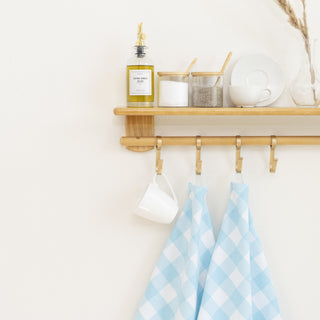 Light blue plaid cotton kitchen towels hanging from a wooden kitchen rail