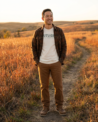 Man in the burnt brown plaid flannel over an Outsider tee with tobacco double knee canvas pants in the Kansas Flint Hills – Artisan Grove fall layering